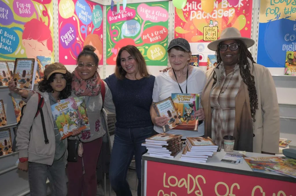 Group posing with children’s books at a colorful booth